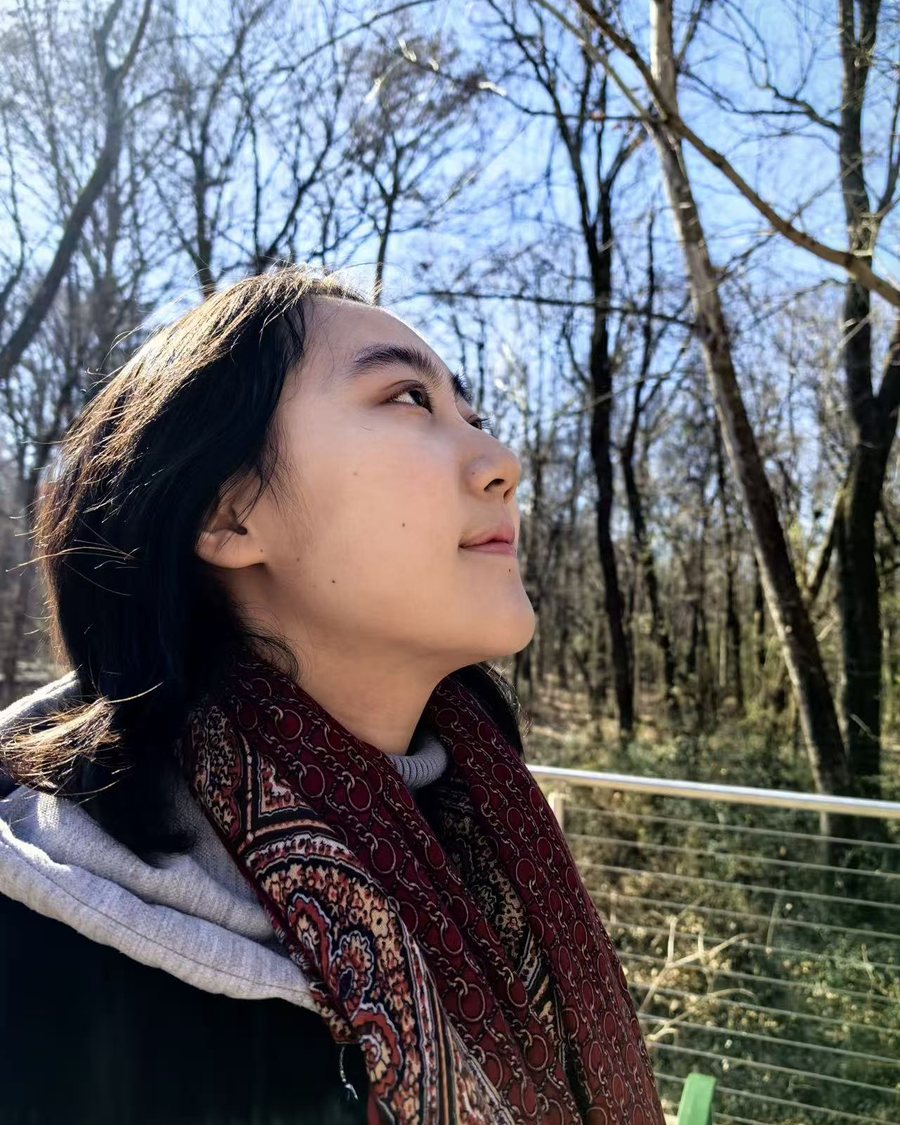 Me outdoors on a sunny winter day, looking up at the sky through bare trees
